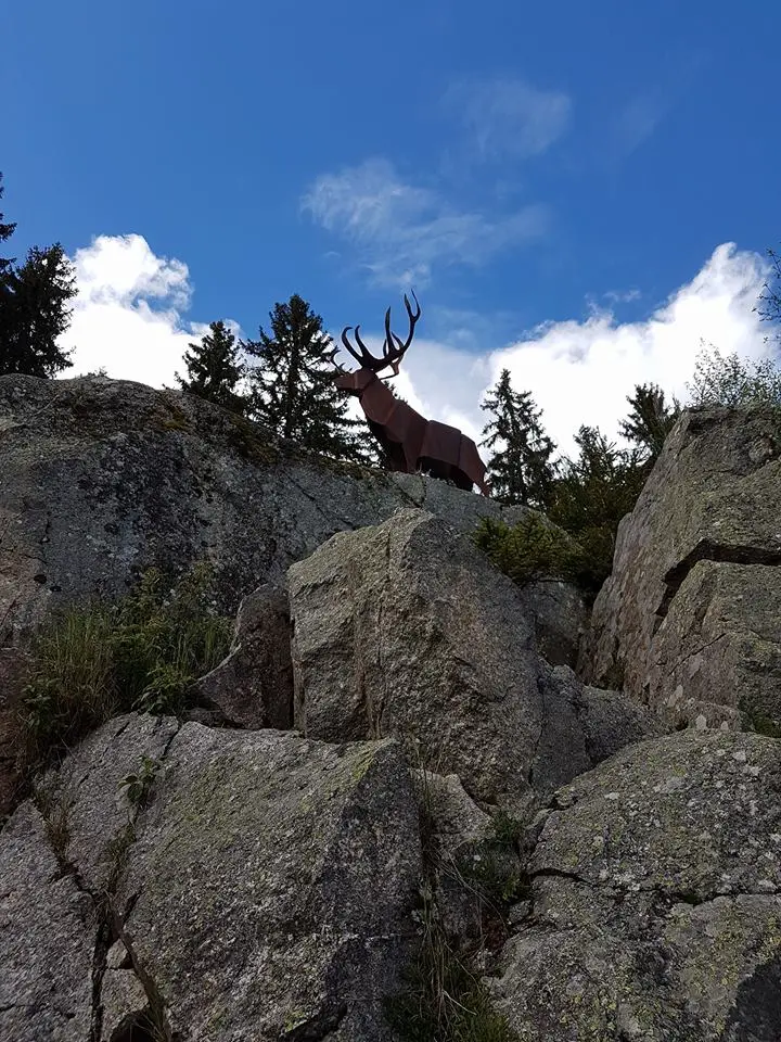 Der Staumauer-Hirsch aus Stahl auf dem Felsen über dem Schluchsee vor blauem Himmel